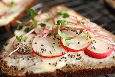 Photo of Tasty toast with radishes, sprouts and chia seeds, closeup