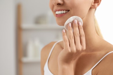 Photo of Smiling woman removing makeup with cotton pad indoors, closeup. Space for text