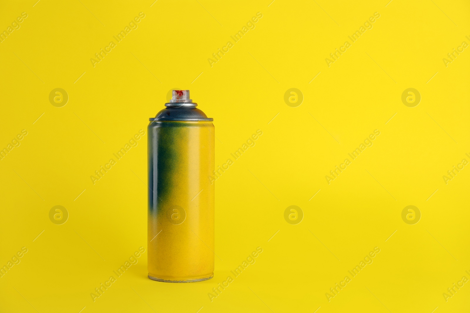 Photo of Used can of spray paint on yellow background. Space for text