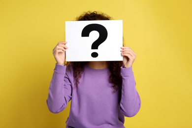 Woman with question mark sign on yellow background