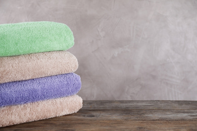 Photo of Stack of clean bath towels on wooden table. Space for text