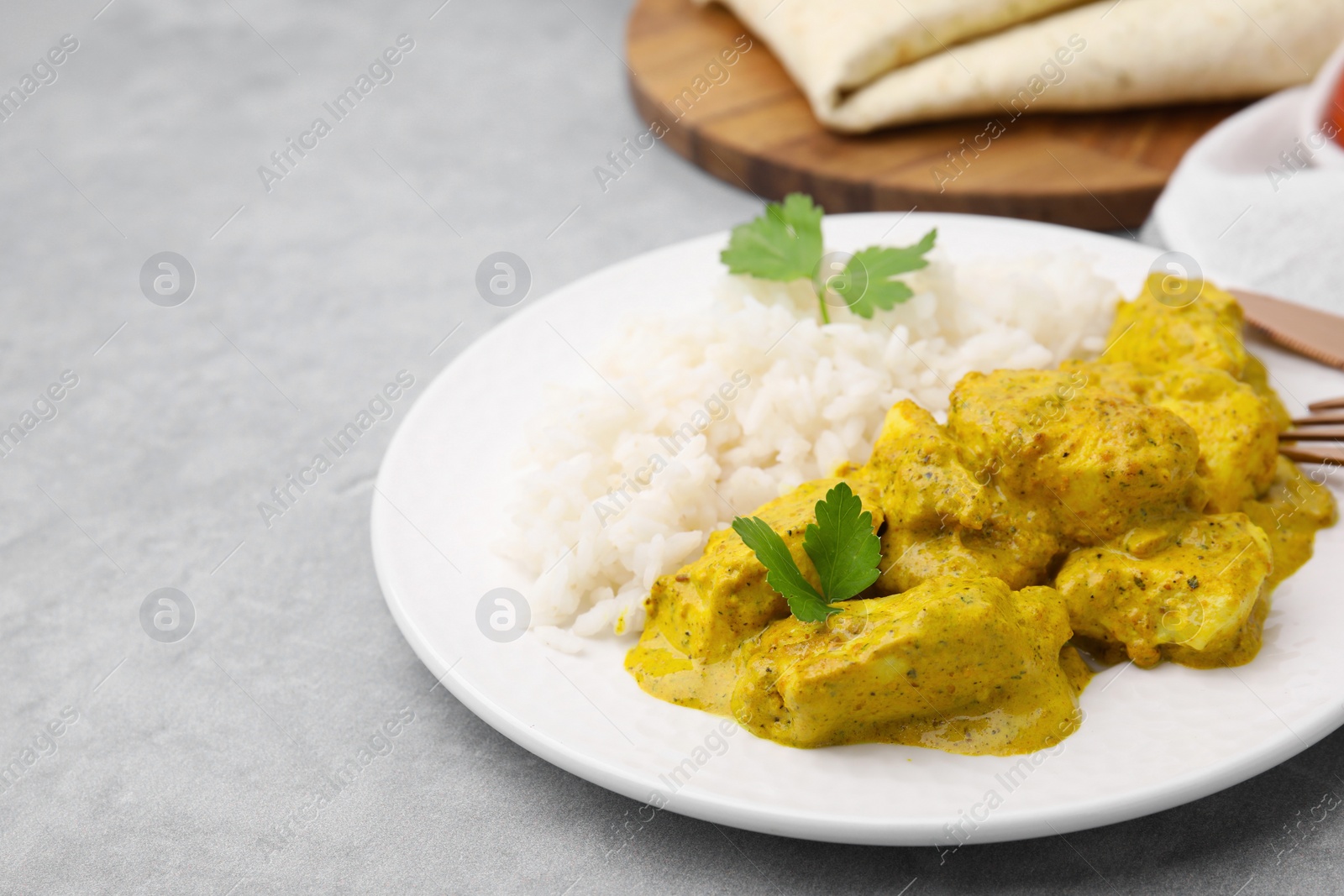 Photo of Delicious rice and chicken with curry sauce on light grey table, closeup. Space for text