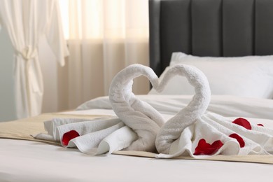 Honeymoon. Swans made of towels and rose petals on bed in room