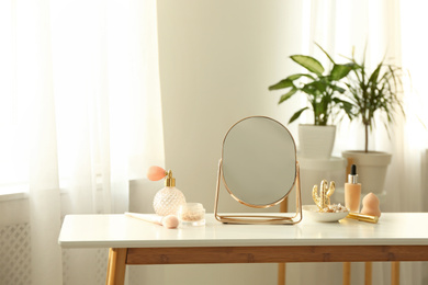 Photo of Mirror and makeup products on white table indoors