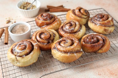 Photo of Tasty cinnamon rolls and sticks on beige textured table