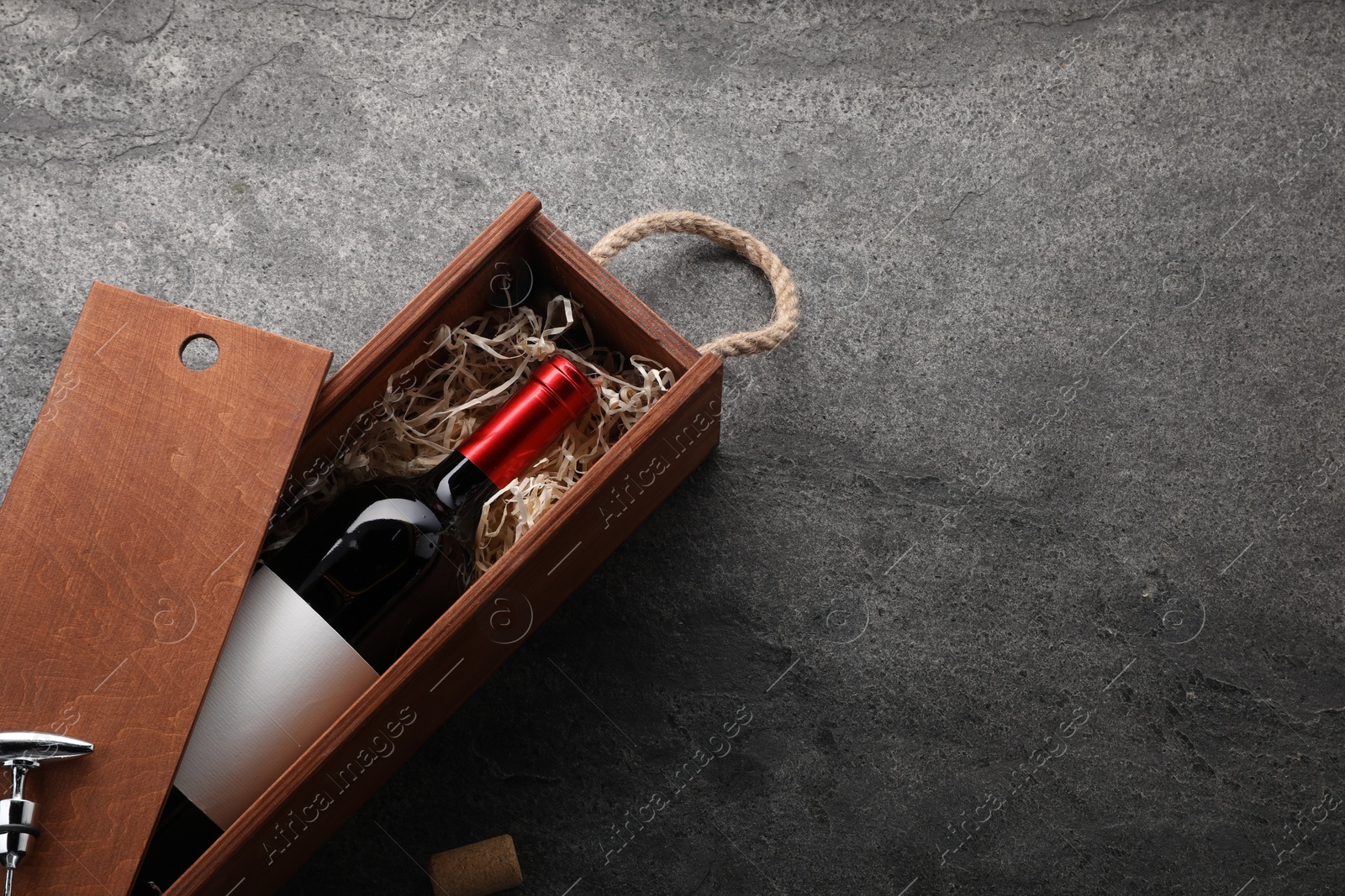 Photo of Bottle of wine in wooden box on dark textured table, above view. Space for text