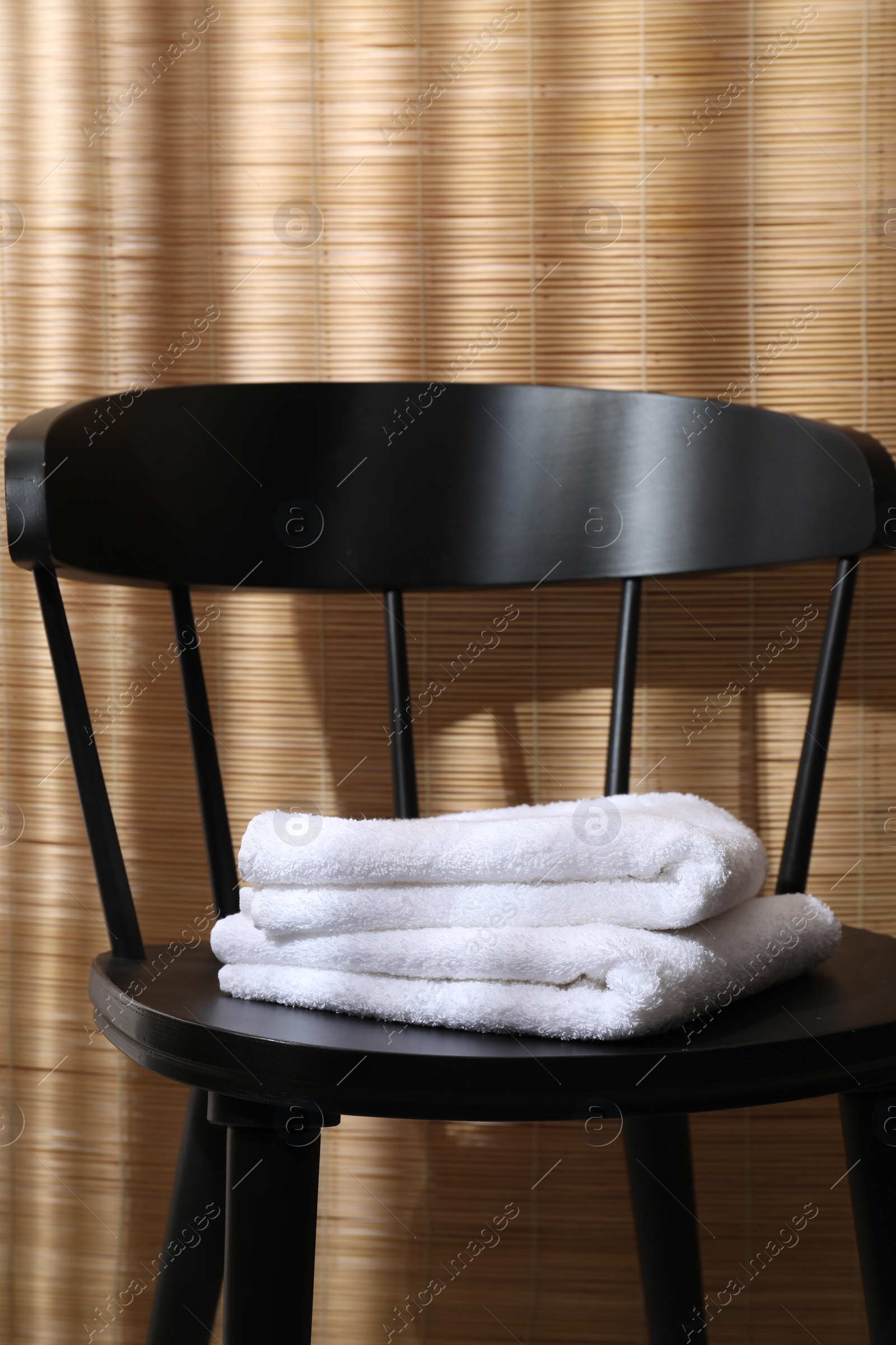 Photo of Stacked soft towels on black chair indoors
