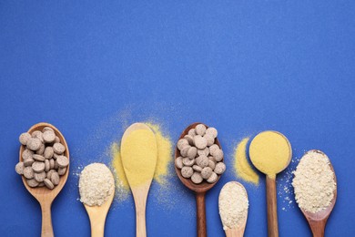 Photo of Spoons with beer yeast powder, flakes and pills on blue background, flat lay. Space for text