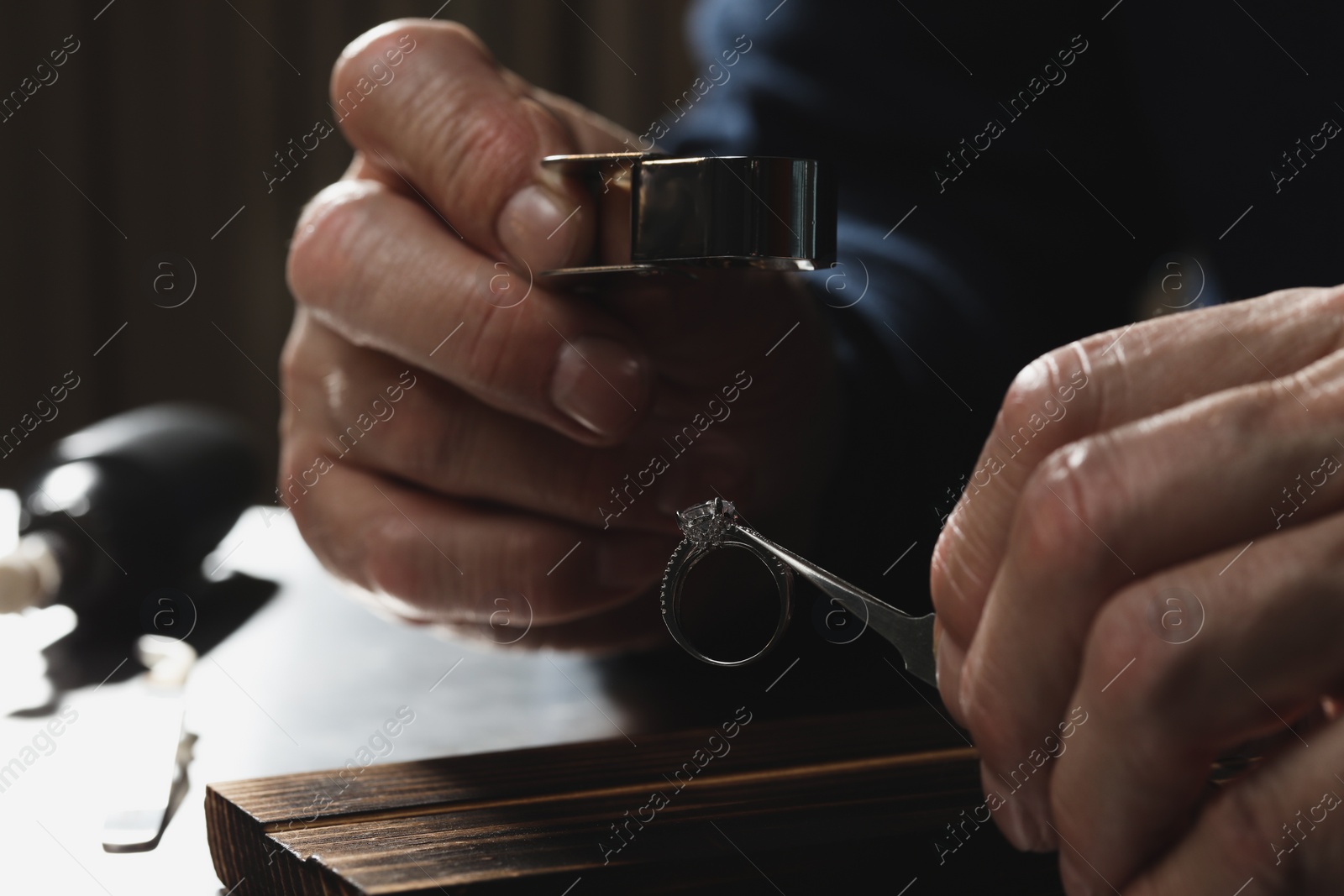 Photo of Professional jeweler working with ring at table, closeup