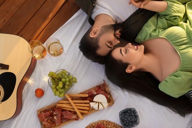 Photo of Romantic date. Beautiful couple resting on picnic blanket, top view