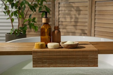 Wooden tray with spa products on bath tub in bathroom