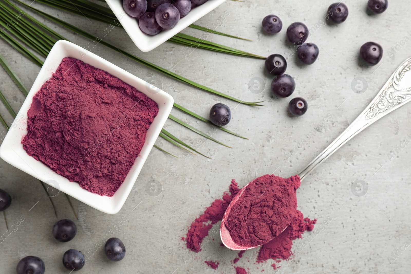 Photo of Acai powder and berries on grey background, flat lay