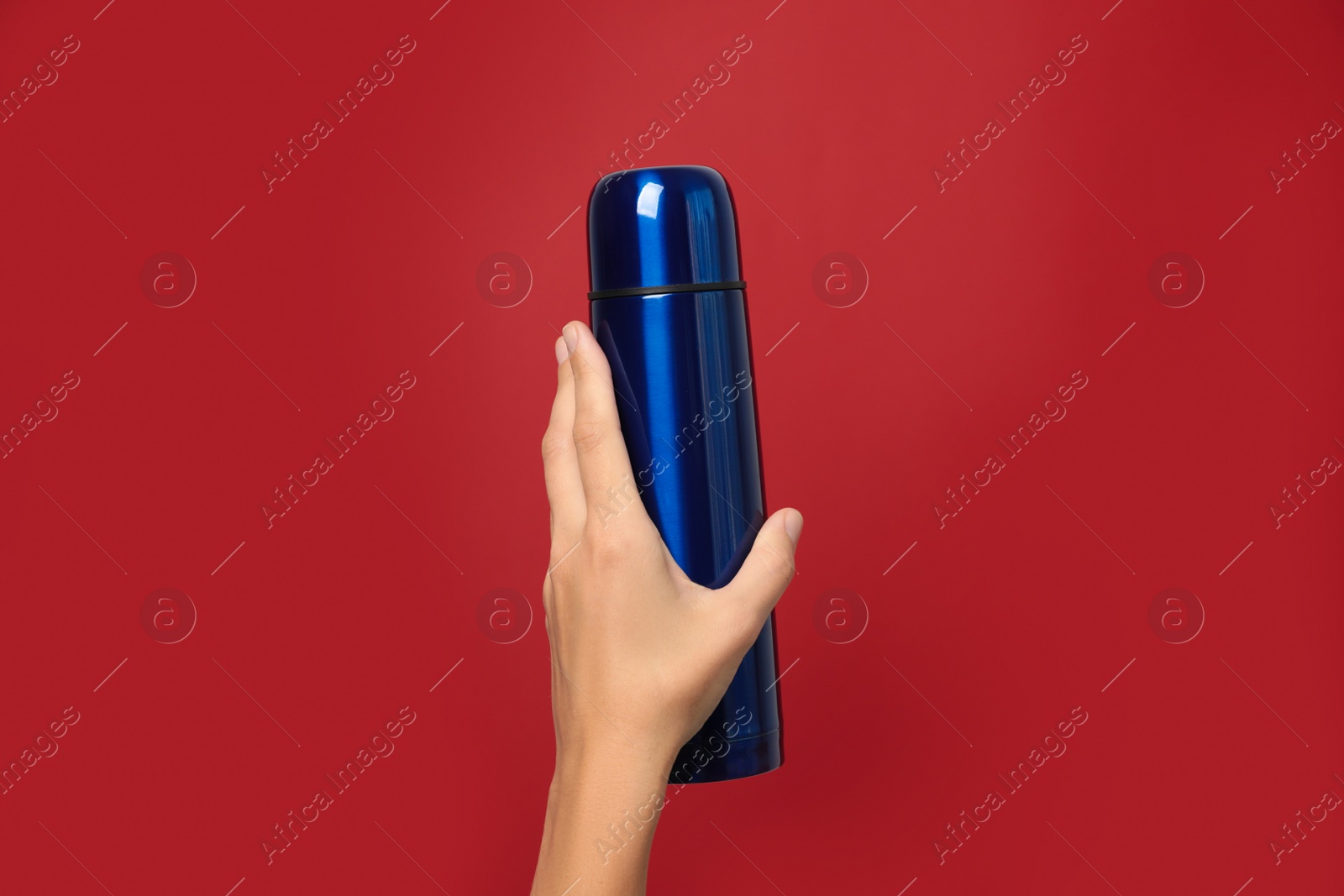 Photo of Woman holding modern blue thermos on red background, closeup