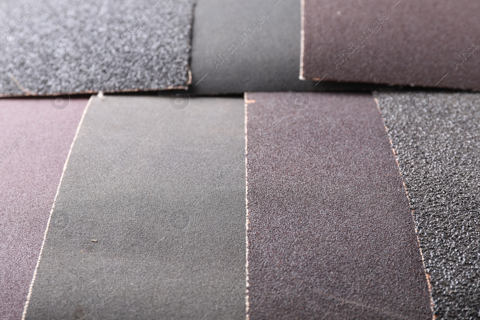 Photo of Many sheets of sandpaper as background, closeup