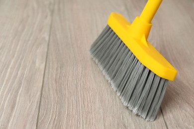 Photo of Sweeping wooden floor with plastic broom, closeup. Space for text