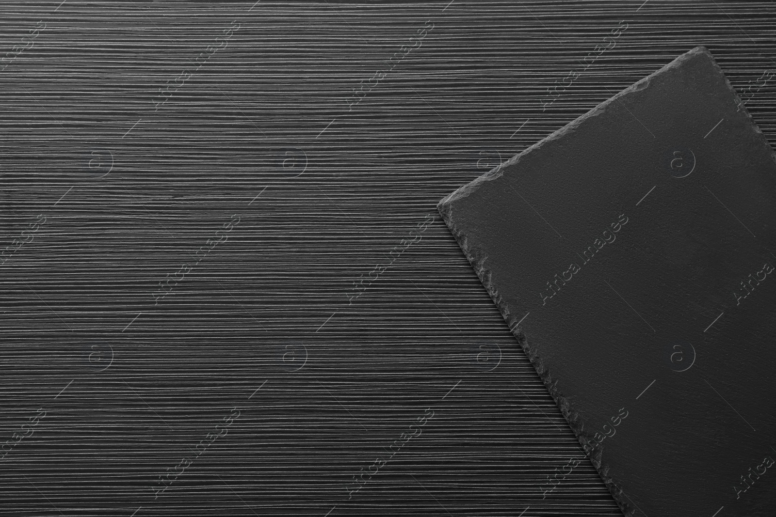 Photo of Slate board on black wooden table, top view. Space for text