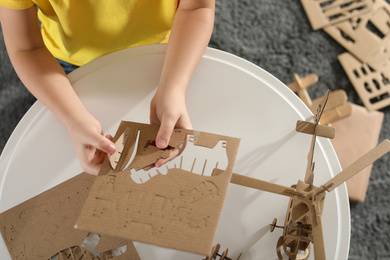 Little boy making carton toys at table indoors, top view. Creative hobby