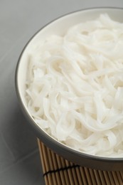 Bowl with cooked rice noodles on light grey table, closeup