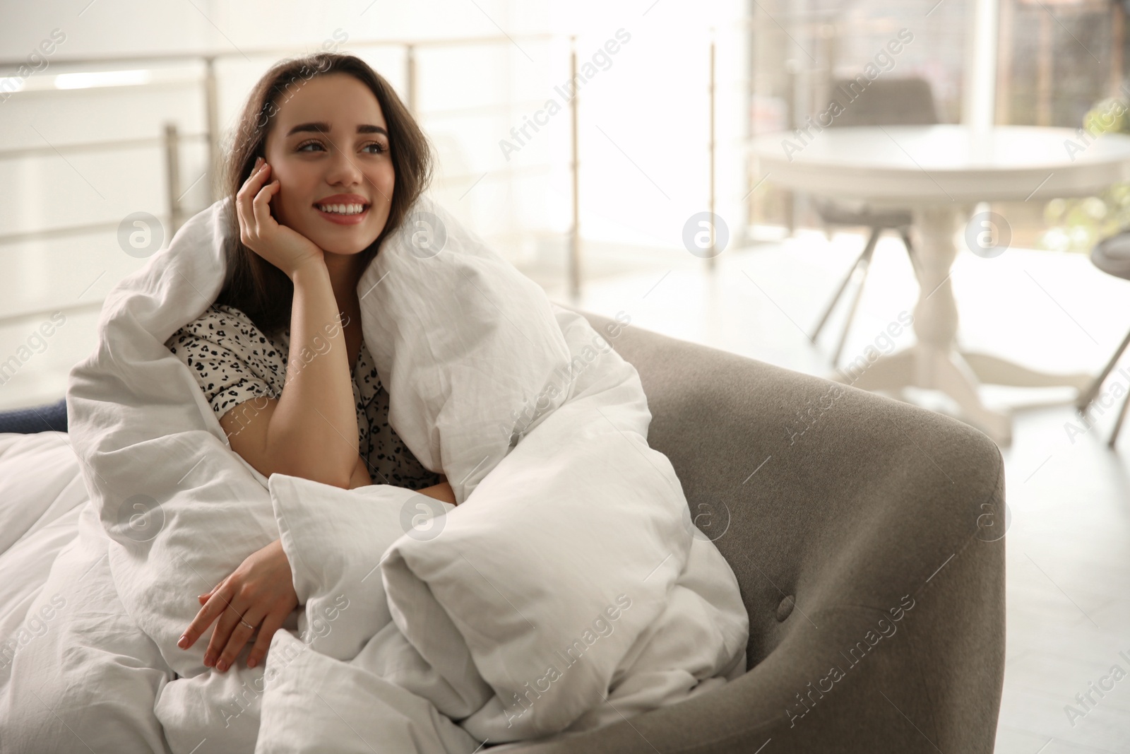 Photo of Beautiful young woman wrapped with soft blanket relaxing on sofa at home