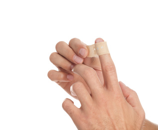 Man putting sticking plaster onto finger on white background, closeup