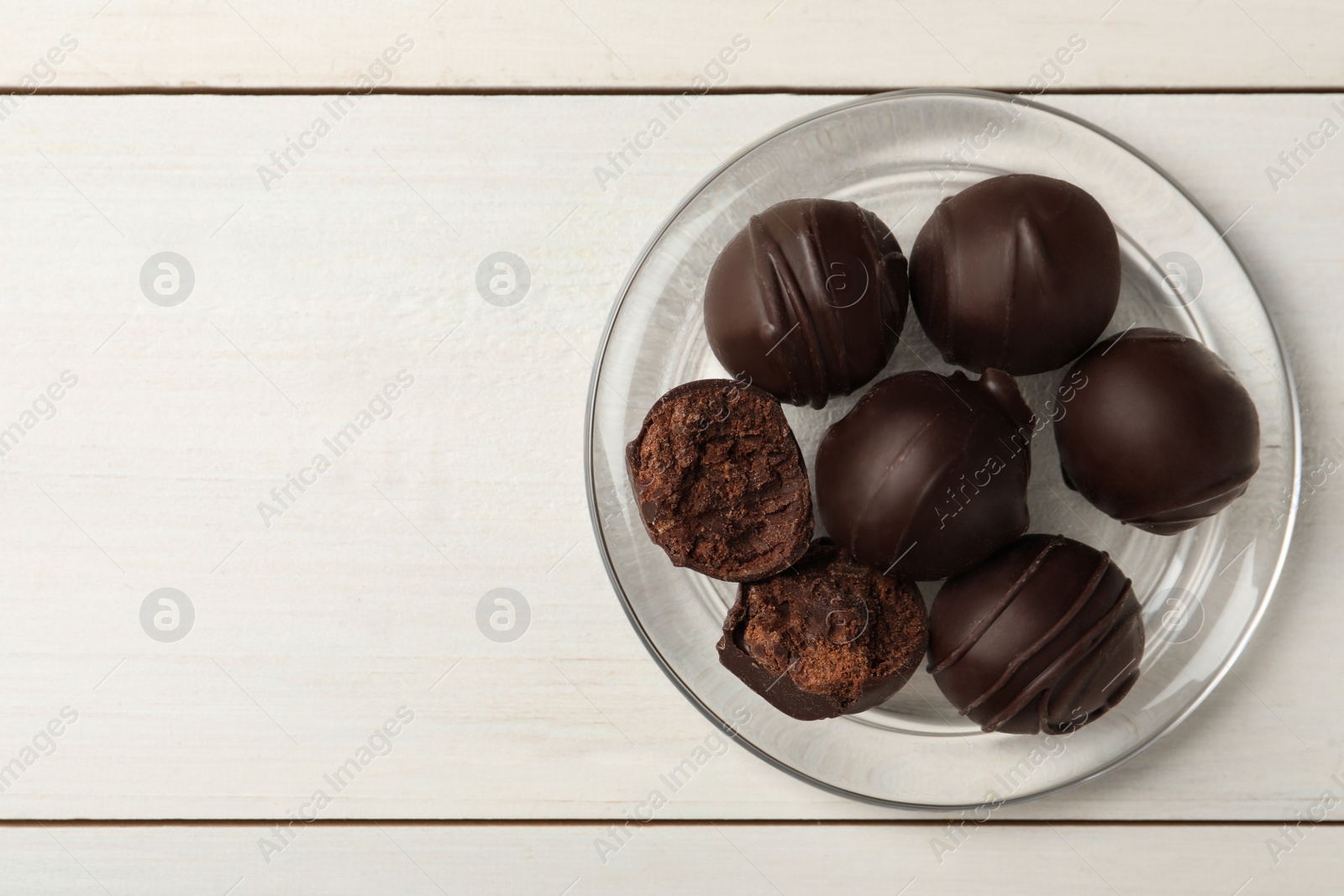 Photo of Many delicious chocolate truffles on white wooden table, top view. Space for text