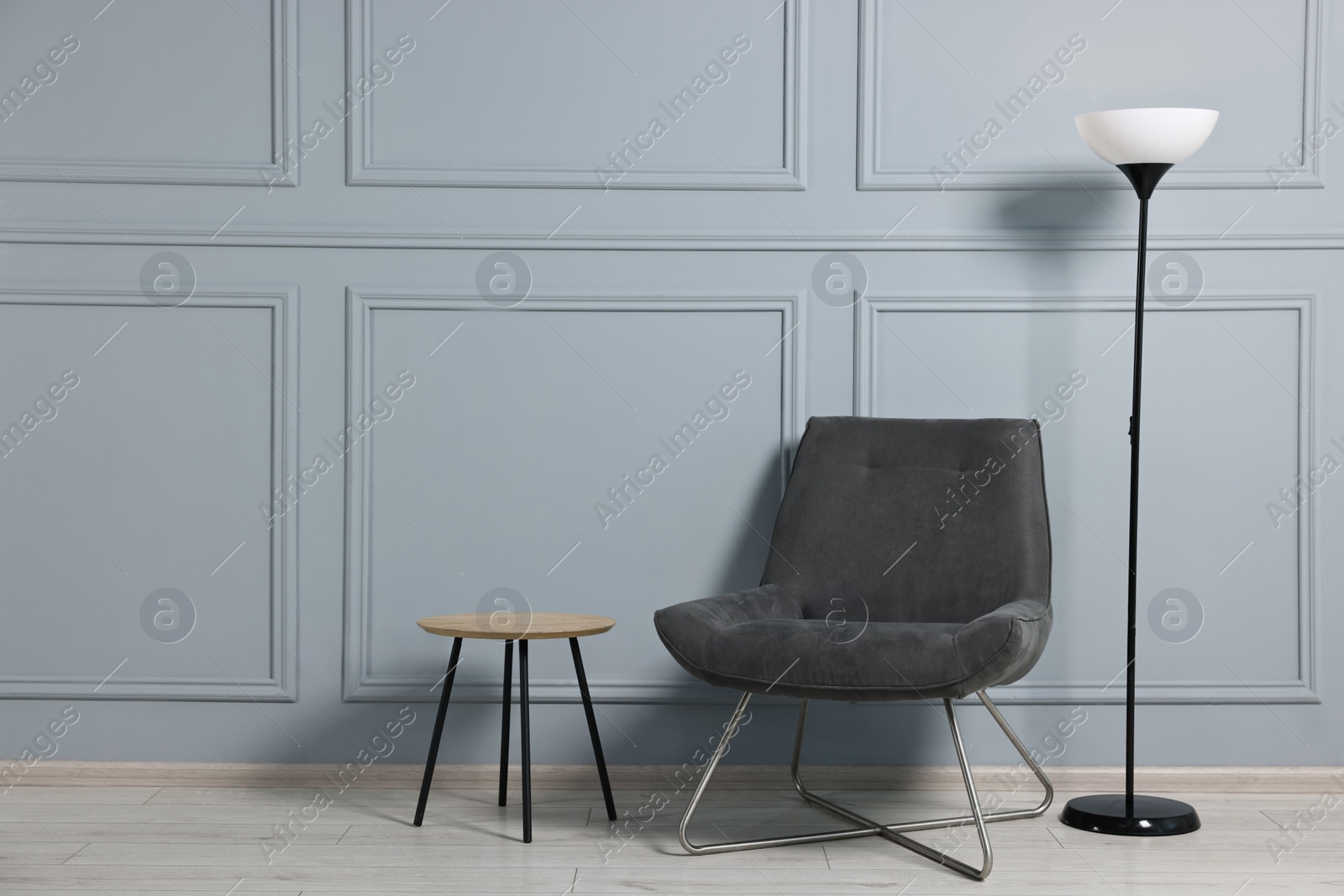 Photo of Comfortable armchair, side table and lamp indoors, space for text