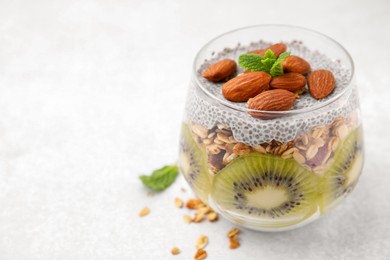 Delicious dessert with kiwi, chia seeds and almonds on white table, closeup. Space for text