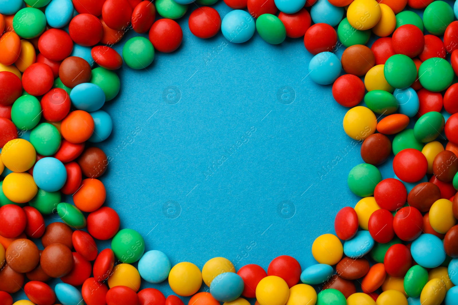 Photo of Frame of tasty colorful candies on blue background, flat lay. Space for text