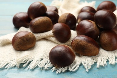 Roasted edible sweet chestnuts on light blue wooden table, closeup