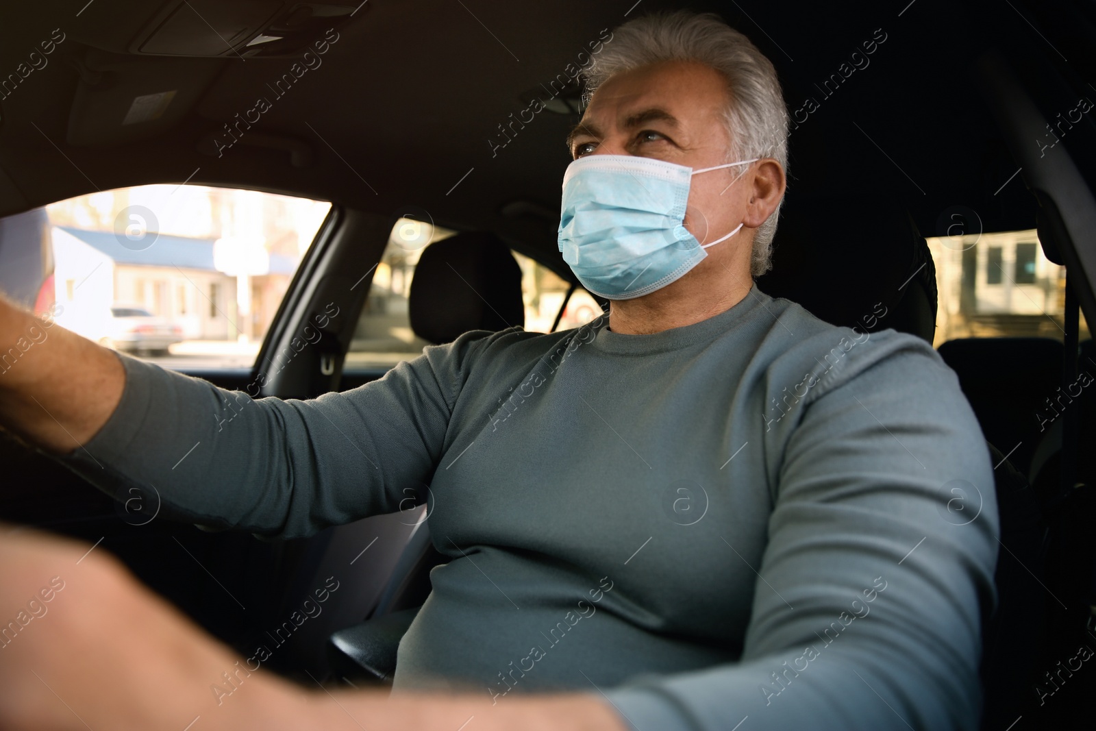 Photo of Senior man with medical mask in car. Virus protection