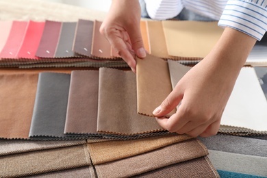 Young woman choosing among upholstery fabric samples, closeup. Interior design