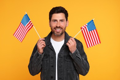 Photo of 4th of July - Independence Day of USA. Happy man with American flags on yellow background