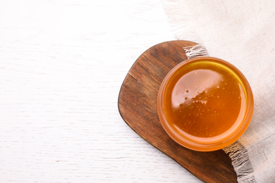 Photo of Tasty aromatic honey on white wooden table, flat lay. Space for text