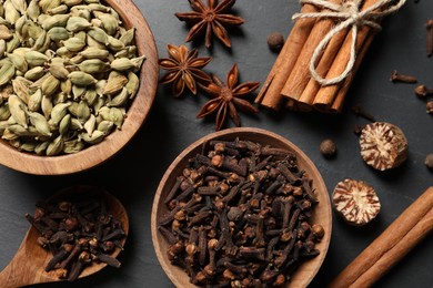 Photo of Different spices in bowls on dark gray textured table, flat lay