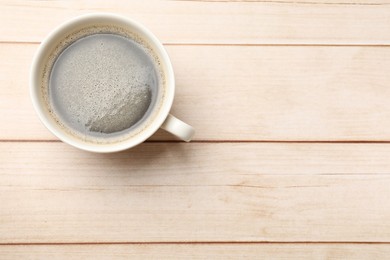 Photo of Cup of aromatic coffee on light wooden table, top view. Space for text