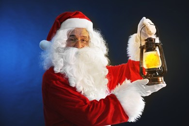 Photo of Merry Christmas. Santa Claus with vintage lantern on dark blue background