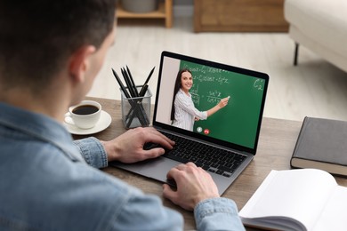 E-learning. Young man having online lesson with teacher via laptop at home, closeup