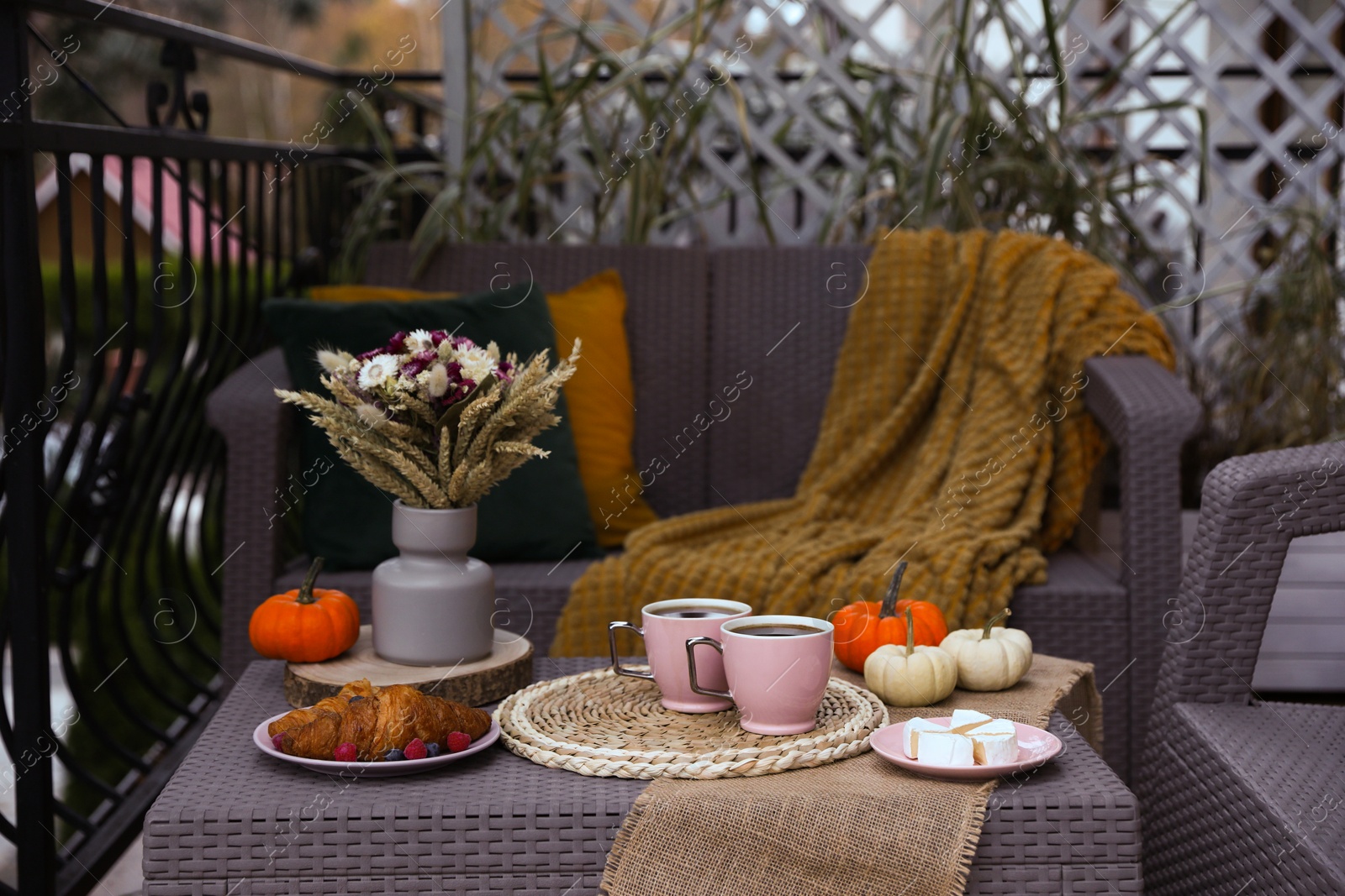 Photo of Rest on terrace with rattan furniture. Drink, dessert and autumn decor on table