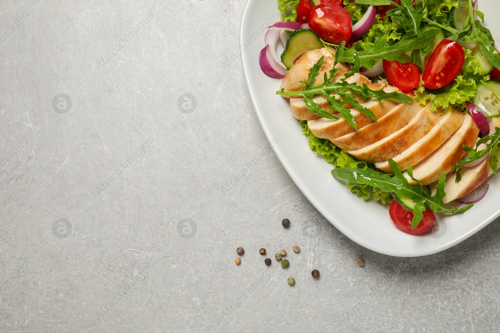 Photo of Delicious salad with meat, arugula and vegetables on grey table, flat lay. Space for text