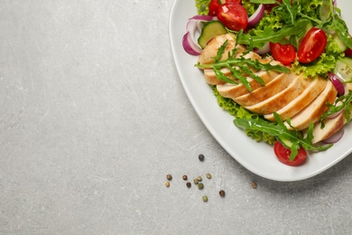 Delicious salad with meat, arugula and vegetables on grey table, flat lay. Space for text