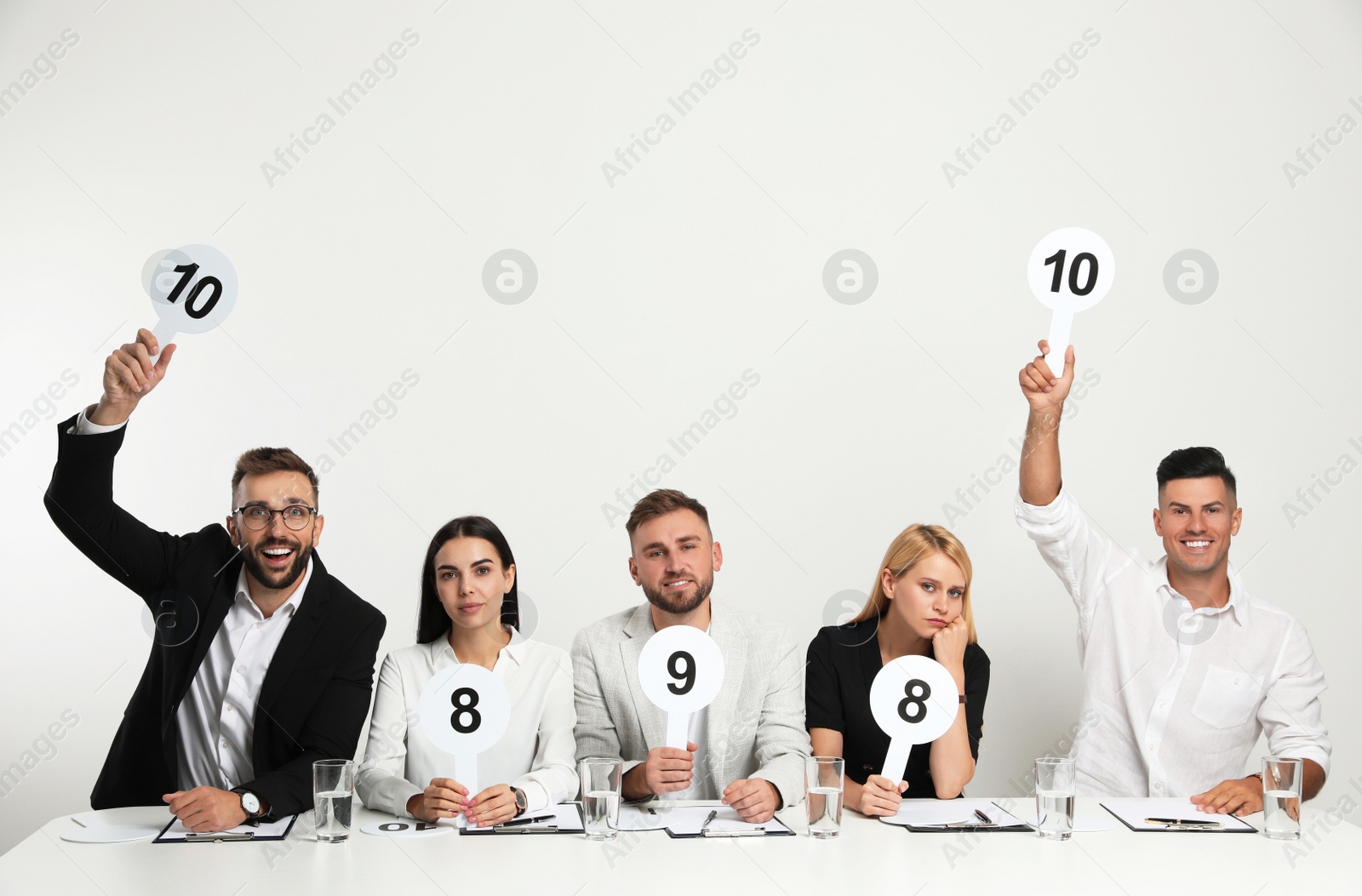 Photo of Panel of judges holding different score signs at table on white background