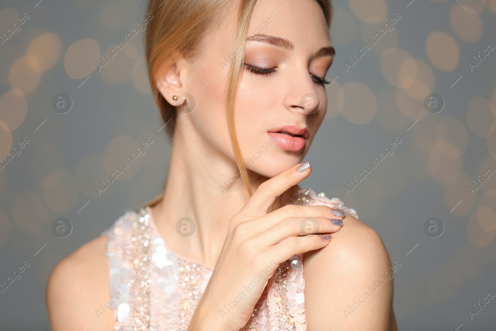 Photo of Beautiful young woman with shiny manicure on blurred background. Nail polish trends