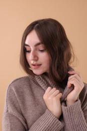 Photo of Portrait of beautiful young woman in warm sweater on brown background