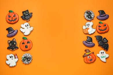 Photo of Different decorated gingerbread cookies on orange background, flat lay with space for text. Halloween celebration