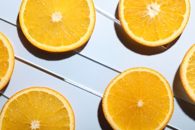 Slices of juicy orange on light blue background, flat lay