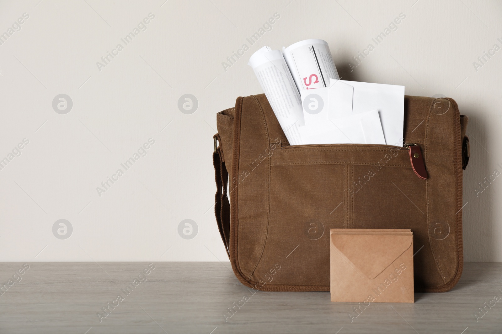 Photo of Postman's bag full of letters and newspapers on wooden background. Space for text