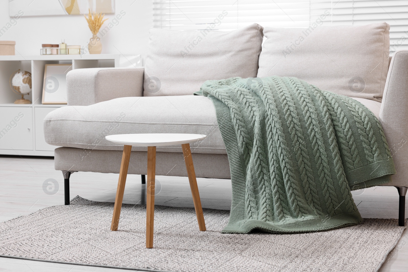 Photo of Knitted plaid on comfortable sofa in living room