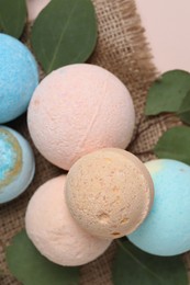 Photo of Bath bombs and eucalyptus leaves on burlap fabric, flat lay