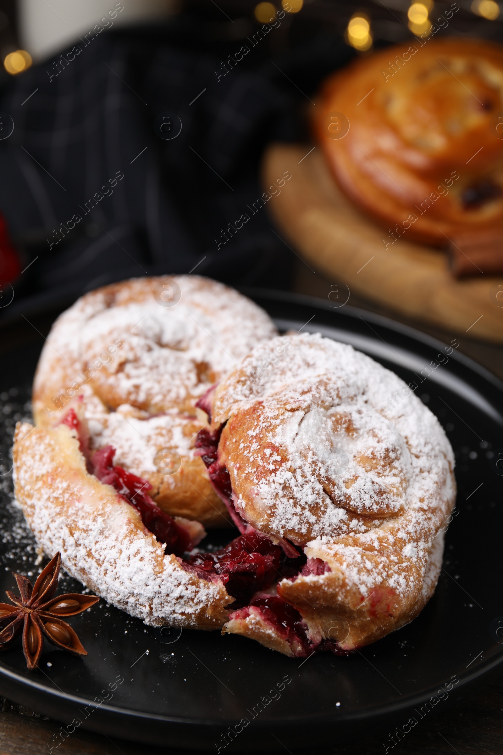 Photo of Delicious buns with berries, anise and sugar powder on table, closeup