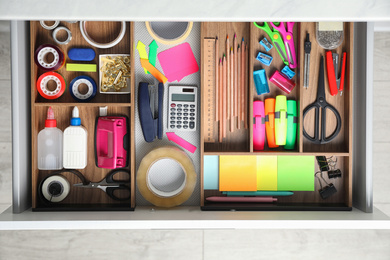 Photo of Different stationery in open desk drawer, top view